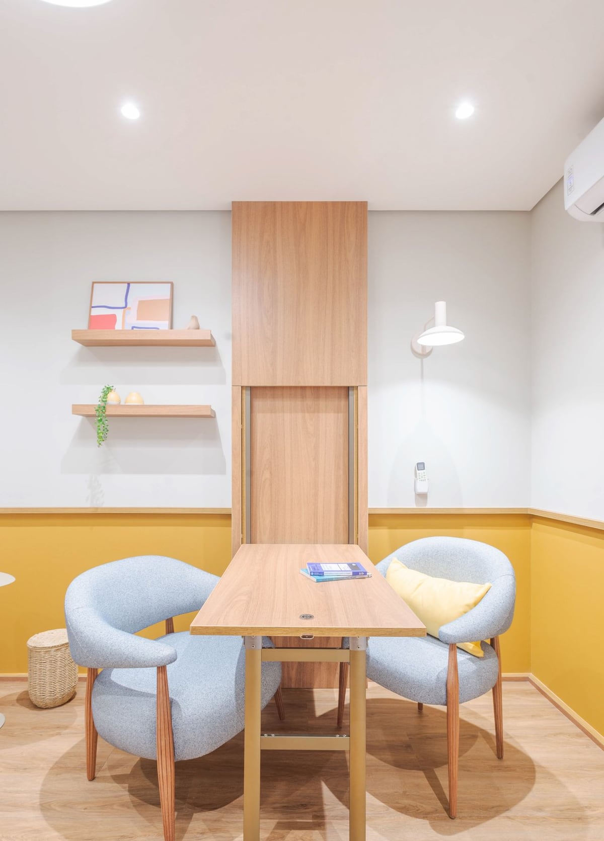 Sala de atendimento com duas poltronas, mesa de apoio e prateleiras.